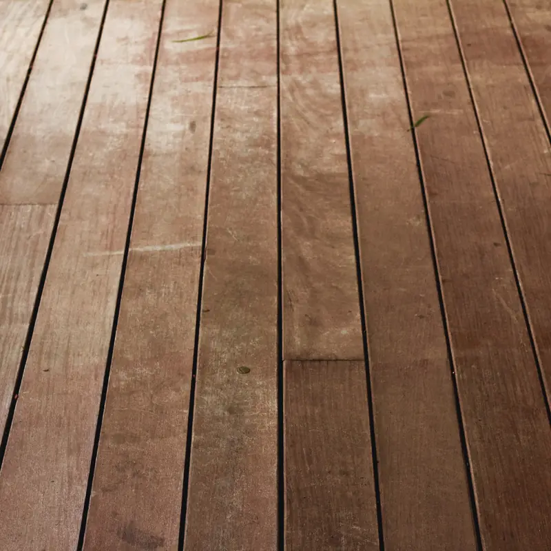 Weathered red-brown merbau deck boards before oiling, with staggered joins across the run.